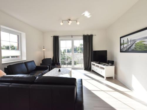 a living room with a black couch and a tv at Charming Apartment in Oldenburg in Holstein with Terrace in Oldenburg in Holstein