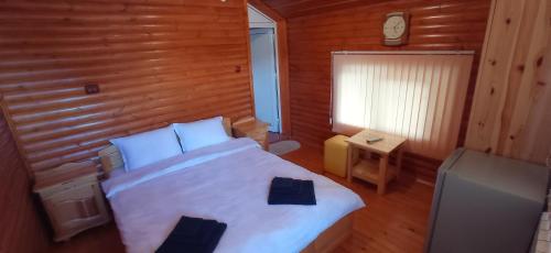 een slaapkamer met een wit bed en een houten muur bij Къща за гости Джамбазови in Sarnitsa