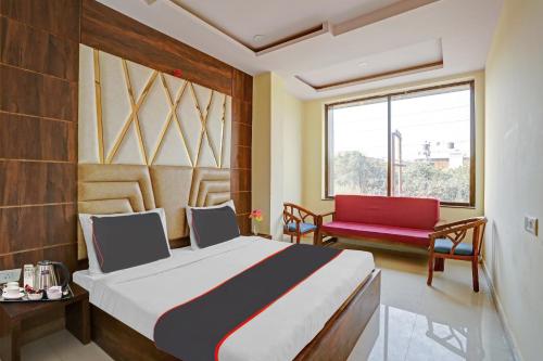 - une chambre avec un lit et une chaise rouge dans l'établissement Capital O Mt Corporate Stays Near Iskcon Temple Noida, à Indirapuram