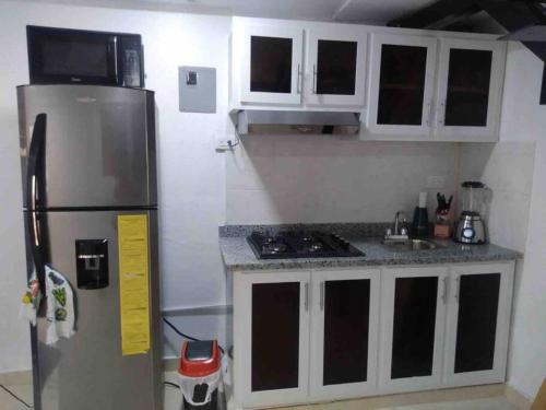 a kitchen with a stainless steel refrigerator and white cabinets at Alojamiento paulino in Santiago de los Caballeros