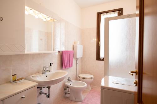 bagno con lavandino, servizi igienici e specchio di Appartamento La Rosa a Roe