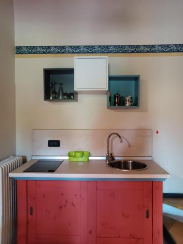 una cucina con mobile rosso e lavandino di OASI DEL GARDA 2 a Monzambano