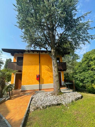 una casa gialla con un albero di fronte di OASI DEL GARDA 2 a Monzambano