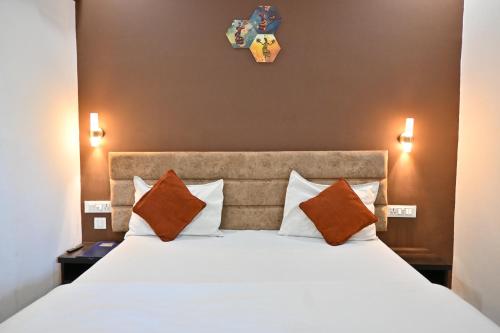 una camera da letto con un grande letto bianco con cuscini arancioni di K & K Hotel a Jabalpur