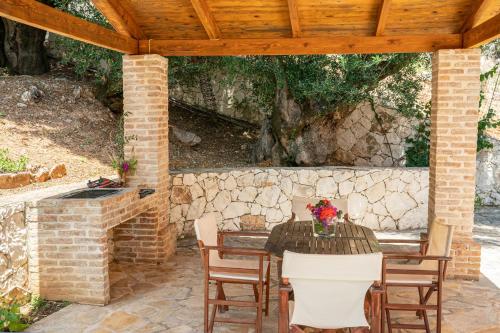 a patio with a table and chairs and a stone wall at Villa Apollo up to 8px, private pool in Fiskardho