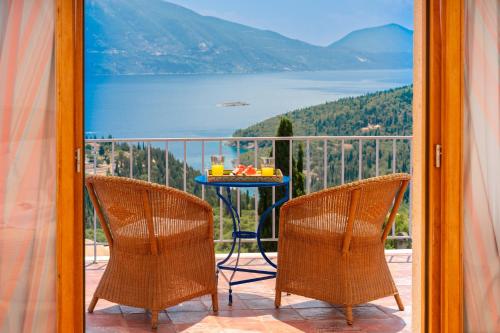 a table and chairs on a balcony with a view of the water at Villa Apollo up to 8px, private pool in Fiskardho