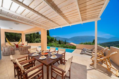 a patio with a table and chairs and a pool at Villa Apollo up to 8px, private pool in Fiskardho