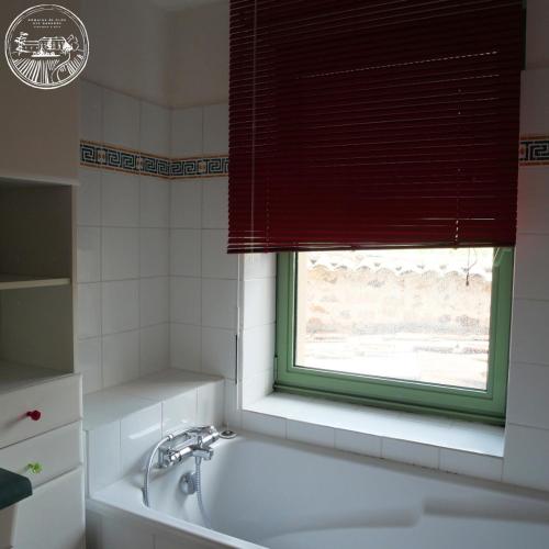 une salle de bain avec une baignoire et une fenêtre dans l'établissement Gîte de la vieille vigne, à Fleurie