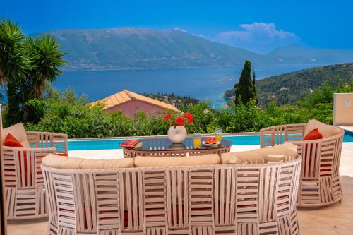 a patio with a table and chairs and a view of the water at Villa Apollo up to 8px, private pool in Fiskardho