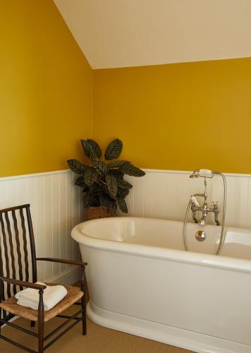 a bath tub in a bathroom with a chair at The Bear Inn, Hodnet in Market Drayton