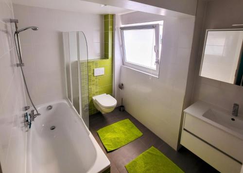 e bagno con vasca, servizi igienici e lavandino. di Calm and modern apartment a Eischen