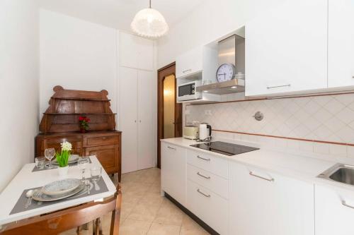 uma cozinha com armários brancos, um lavatório e uma mesa em Lungo Dora Voghera Lovely Suite em Turim