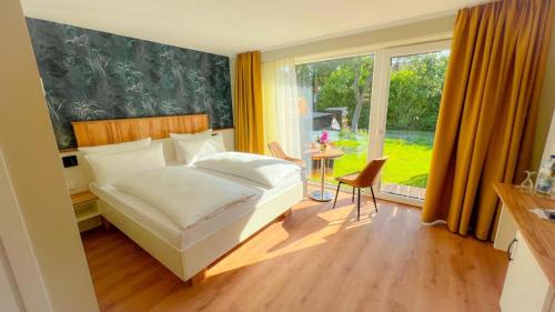 a bedroom with a bed and a large window at Hotel Ostseeland in Warnemünde