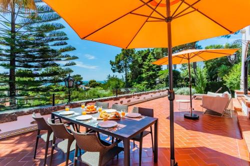 einen Tisch mit Stühlen und einem Sonnenschirm auf einer Terrasse in der Unterkunft Estoril Royal Atlantic Villa with Ocean View in Estoril