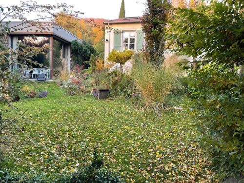 una casa con un patio lleno de hierba y flores en L’atelier d’Alain en Maxéville