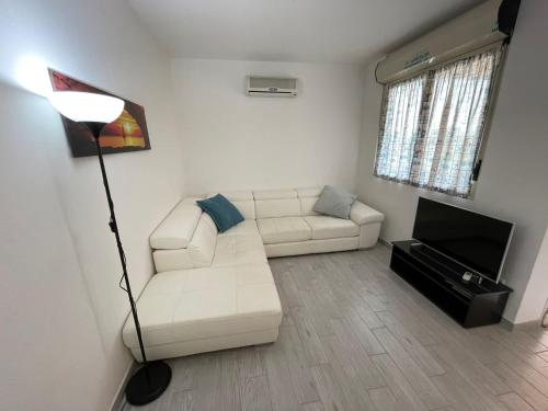 sala de estar con sofá blanco y TV en Rio Home, en Principina a Mare