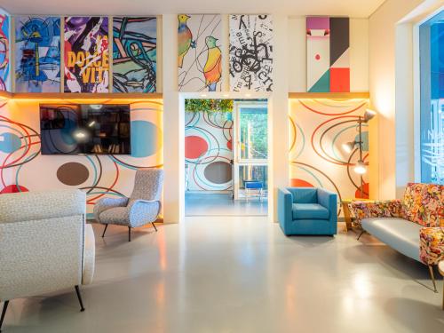 un soggiorno con opere d'arte colorate alle pareti di Hotel Il Nido a Tellaro