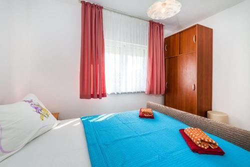 a bedroom with a bed with blue sheets and red napkins at Apartment Nin 531 in Nin
