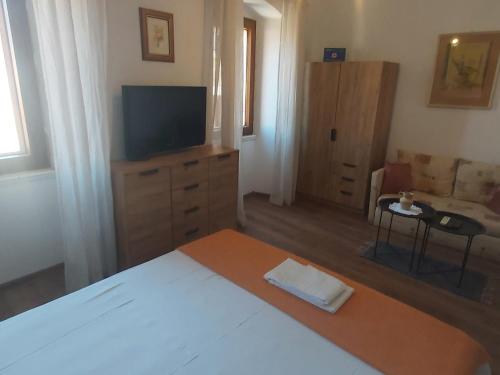 a bedroom with a bed and a tv and a couch at Vila Dora Supetar in Supetar