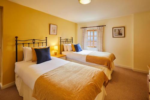 twee bedden in een kamer met gele muren bij Host & Stay - Widger Mews Apartment in Norton