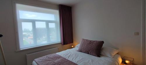 a bedroom with a bed and a window at Maison Rose Plopsaland in De Panne