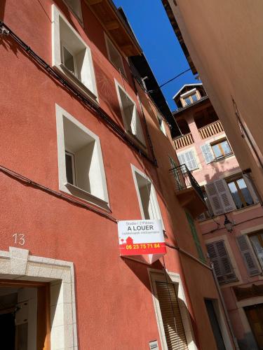 un bâtiment rouge avec un panneau sur son côté dans l'établissement Studio RDC La Tour, à Saint-Étienne-de-Tinée