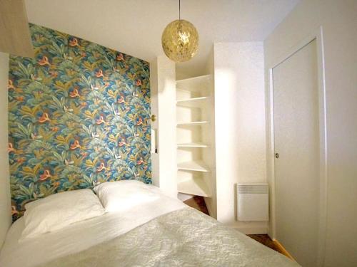 una camera da letto con un letto e una parete floreale di Appartement avec balcon Le nid doré - PLACE MORNY a Deauville