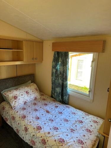 a small bedroom with a bed and a window at Static Caravan - Plymouth - Costal Location in Plymouth