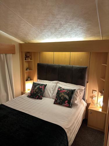 a bed with a black headboard and two pillows on it at Static Caravan - Plymouth - Costal Location in Plymouth