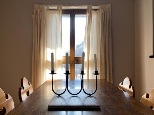 une table à manger avec trois bougies et une fenêtre dans l'établissement Dagli Olivari - Casa Ale, à Gromo