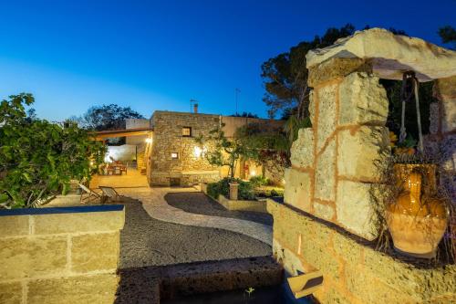 a stone house with a stone wall and a street at Trullo, con giardino privato, a pochi mt dal mare in Torre Suda
