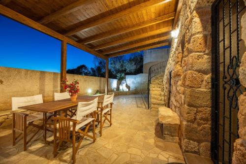 an outdoor dining room with a wooden table and chairs at Trullo, con giardino privato, a pochi mt dal mare in Torre Suda