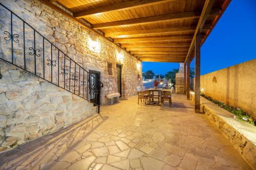 an outdoor patio with a stone wall and a wooden ceiling at Trullo, con giardino privato, a pochi mt dal mare in Torre Suda