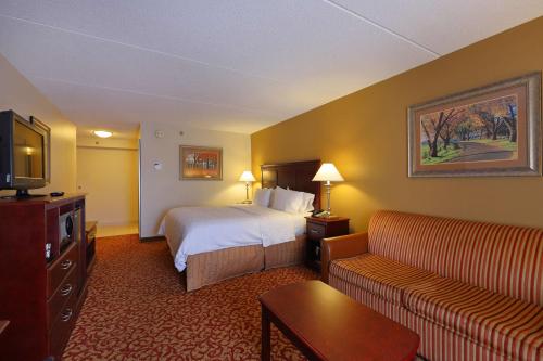 a hotel room with a bed and a couch at Hampton Inn & Suites Charlottesville at the University in Charlottesville