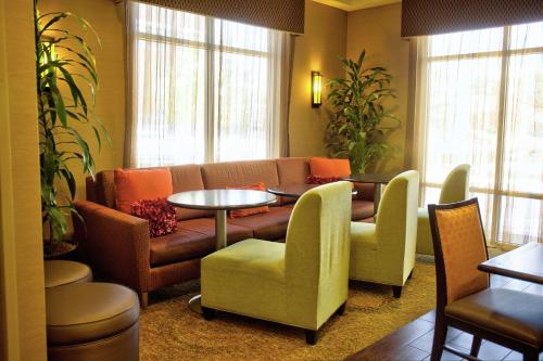 a hotel room with a couch and tables and chairs at Hampton Inn Cedar City in Cedar City