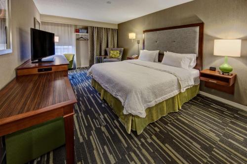 a hotel room with a bed and a flat screen tv at Hampton Inn Charlottesville in Charlottesville