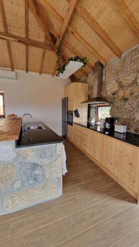 a large kitchen with wooden ceilings and a counter top at CASA DO SOL , Turismo Rural in Celorico de Basto