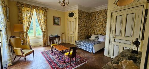 een slaapkamer met een bed, een stoel en een raam bij Château de Montpatey in Couches