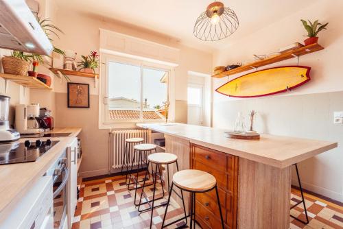 a kitchen with a surfboard on the wall at La Boga L'Auberge à l'ambiance Surf à Biscarrosse Plage in Biscarrosse-Plage