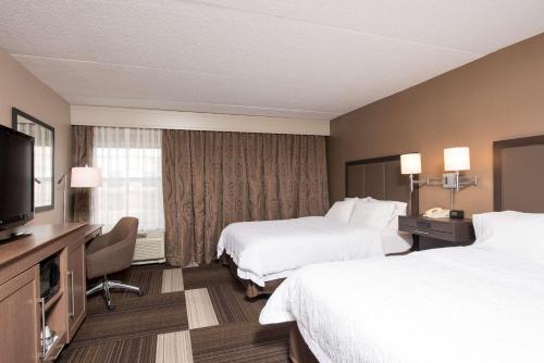a hotel room with two beds and a flat screen tv at Hampton Inn Seymour in Seymour