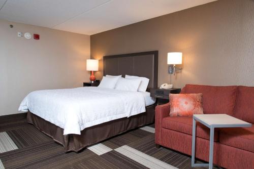 una camera d'albergo con un letto e un divano rosso di Hampton Inn Seymour a Seymour