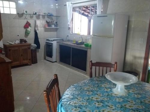 a kitchen with a table and a white refrigerator at Ilhabela Casa Família Feliz in Ilhabela