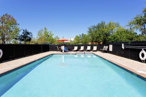 a swimming pool with chairs and an umbrella at Hampton Inn & Suites Port Richey in Port Richey