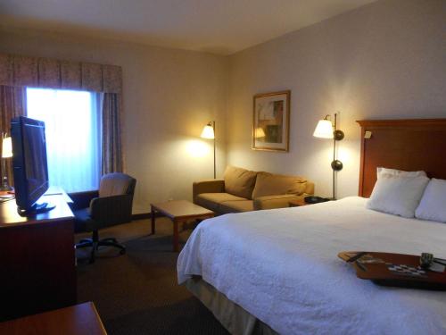 a hotel room with a bed and a couch and a television at Hampton Inn Columbus-International Airport in Gahanna