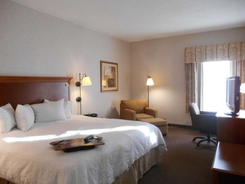 Gahannaにあるハンプトン イン コロンバス インターナショナル エアポートのトレイ付きのベッドが備わるホテルルームです。