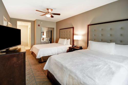 a hotel room with two beds and a flat screen tv at Homewood Suites by Hilton Tampa-Port Richey in Port Richey