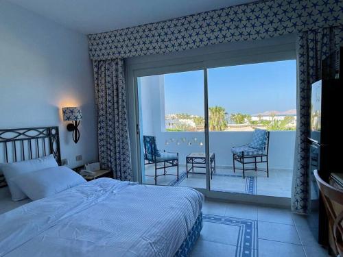 Azure Retreat - Private Luxury Sea View Apartment في شرم الشيخ: غرفة نوم بسرير وشرفة مع كراسي