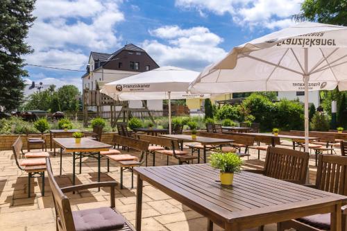 an outdoor patio with tables and chairs and umbrellas at Erzgebirgshotel Freiberger Höhe in Eppendorf
