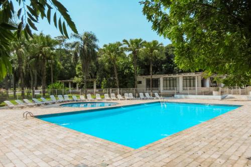 una piscina con tumbonas y árboles en Hotel Monalisa, en Foz do Iguaçu