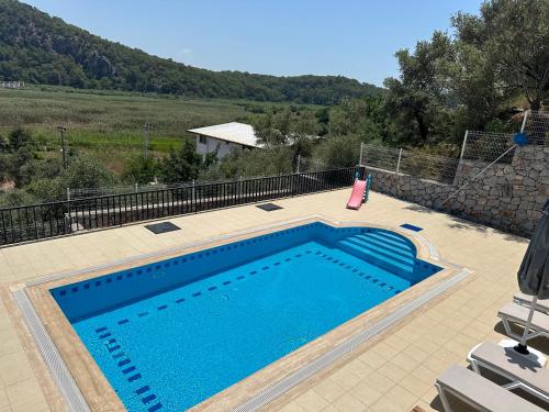 a swimming pool on a patio with a hill in the background at Villa Sarisli 1 in Sarigerme